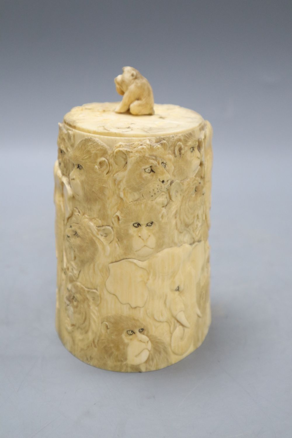 A Japanese ivory box and cover, Meiji Period, carved with elephants, lions, monkeys, etc. (lacking base), overall height including lid